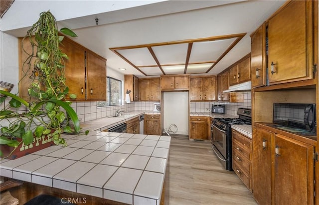 1411 Sequoia Dr, Lake Arrowhead, CA 92352 - kitchen featuring decorative backsplash, tile countertops, stainless steel gas range oven, brown cabinets, and under cabinet range hood