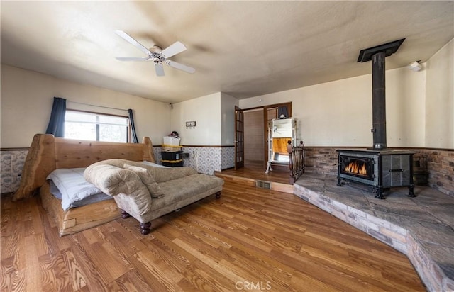 1411 Sequoia Dr, Lake Arrowhead, CA 92352 - bedroom with a wood stove, wainscoting, a ceiling fan, and wood finished floors