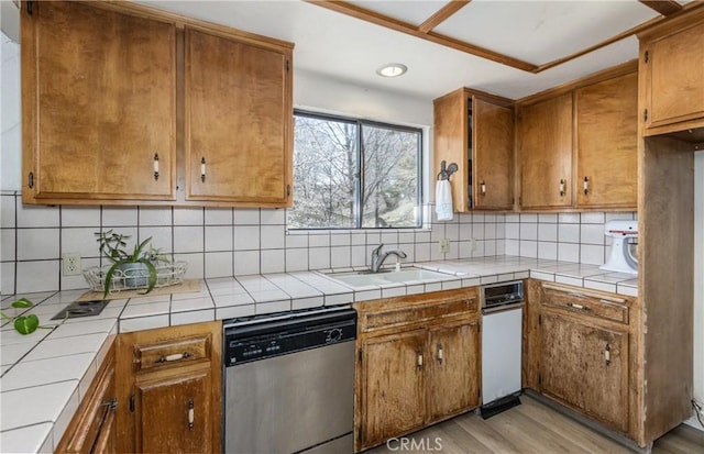 1411 Sequoia Dr, Lake Arrowhead, CA 92352 - kitchen with stainless steel dishwasher, brown cabinetry, tasteful backsplash, a sink, and light wood-style flooring