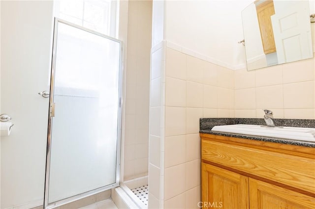 bathroom with vanity, a shower stall, and tile walls