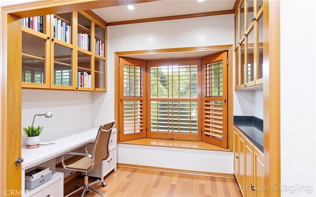 home office featuring built in study area, crown molding, and light wood-type flooring
