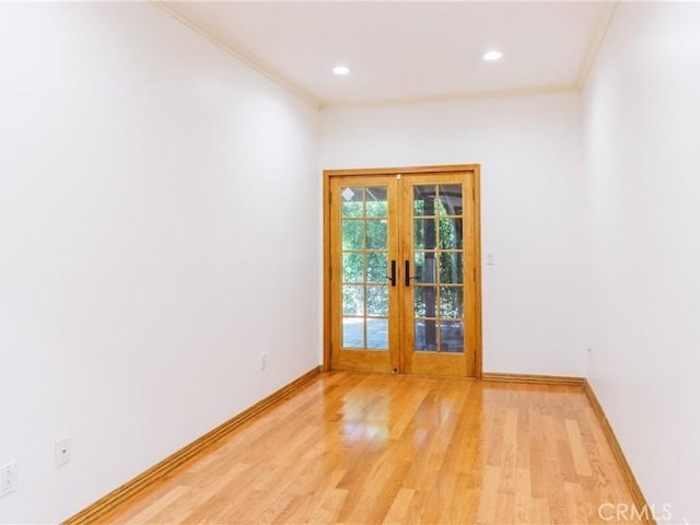 empty room featuring french doors, crown molding, baseboards, light wood finished floors, and recessed lighting