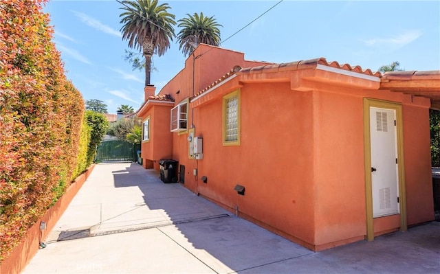 view of home's exterior featuring crawl space, a gate, a tile roof, and stucco siding