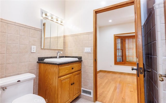 bathroom with visible vents, tile walls, wood finished floors, vanity, and toilet
