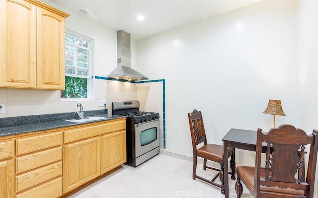 kitchen featuring light brown cabinets, wall chimney range hood, stainless steel range with gas cooktop, recessed lighting, and a sink