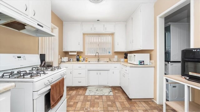 kitchen with a sink, light countertops, under cabinet range hood, and white appliances