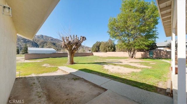view of yard featuring a fenced backyard, a mountain view, and a patio area