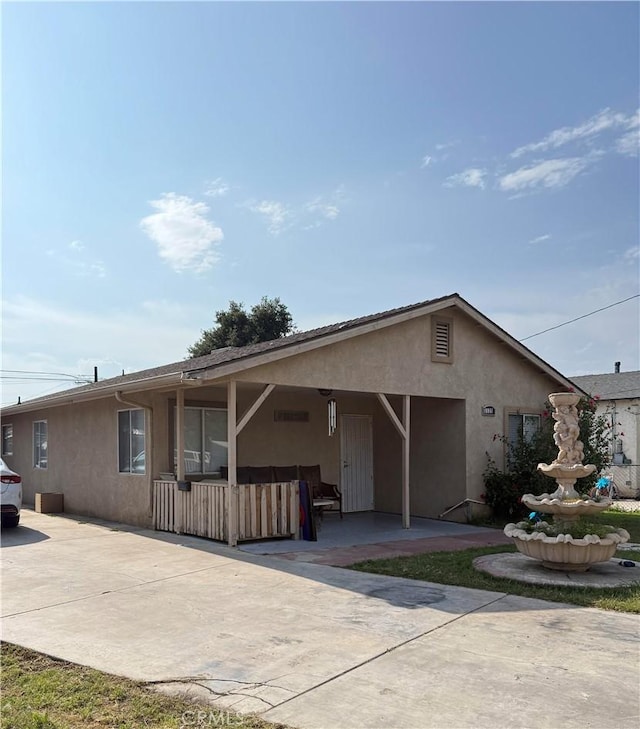 ranch-style house featuring an attached carport, a patio, driveway, and stucco siding