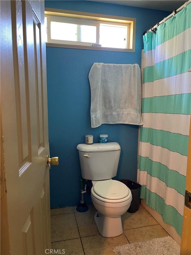bathroom with tile patterned floors, toilet, and curtained shower