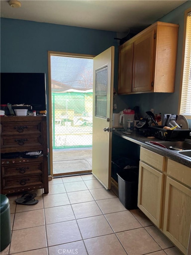 kitchen featuring a sink, light tile patterned flooring, and dark countertops