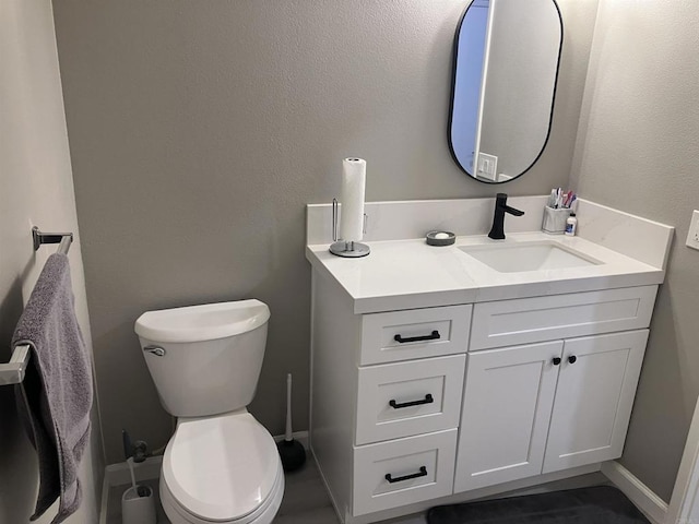 bathroom featuring vanity, baseboards, and toilet