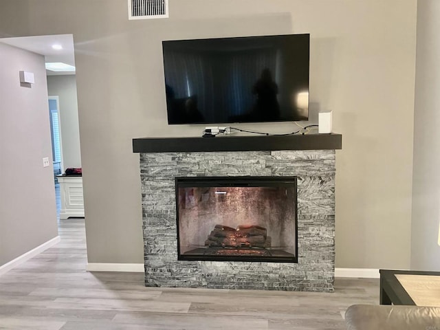 interior details with baseboards, visible vents, wood finished floors, and a fireplace