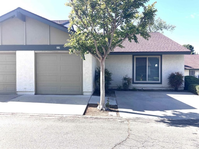 single story home featuring a shingled roof, concrete driveway, stucco siding, and an attached garage
