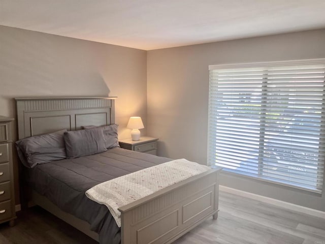 bedroom with baseboards, multiple windows, and wood finished floors