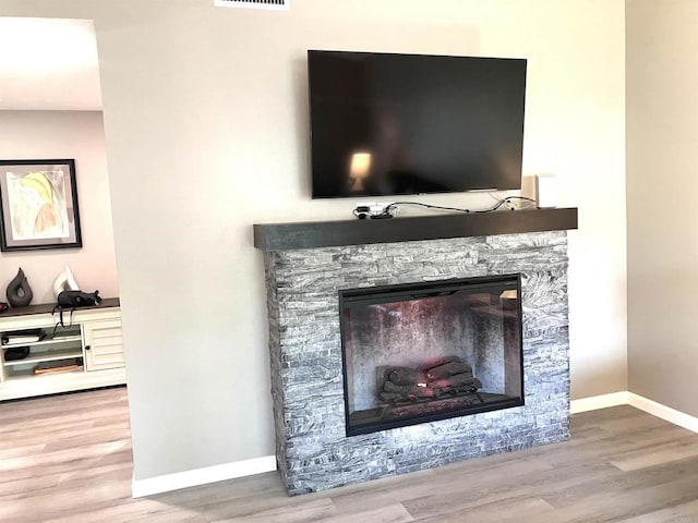 room details with baseboards, a fireplace, wood finished floors, and visible vents