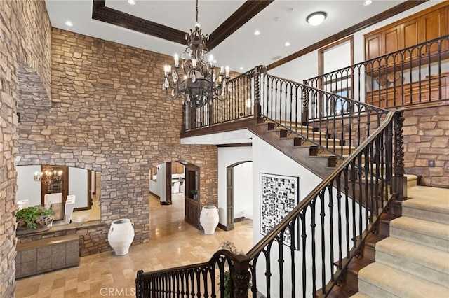stairs with crown molding, arched walkways, recessed lighting, and an inviting chandelier