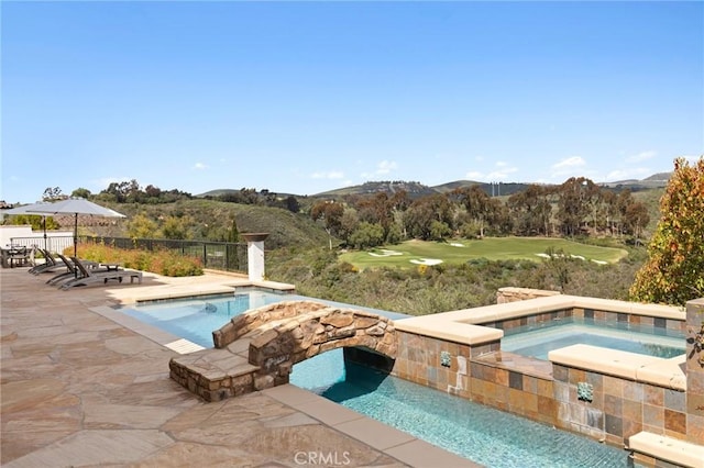 pool with fence, view of golf course, an in ground hot tub, a mountain view, and a patio