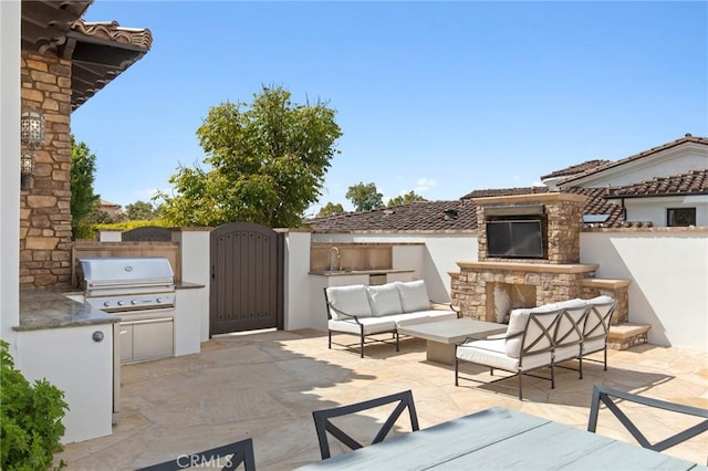 view of patio with fence, a grill, area for grilling, a gate, and an outdoor living space with a fireplace