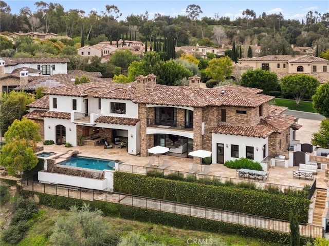 rear view of property with a balcony, a fenced backyard, stucco siding, an outdoor living space, and a tiled roof