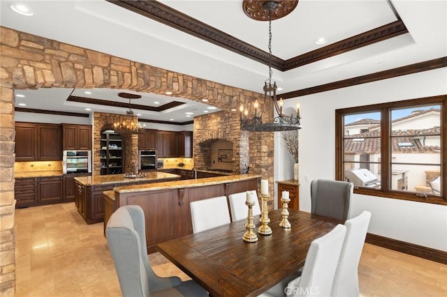 dining space featuring ornamental molding, decorative columns, a chandelier, and a tray ceiling