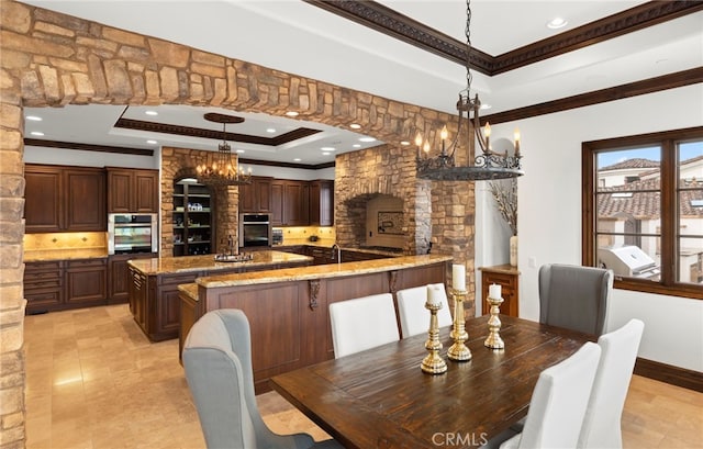 dining space with crown molding, a tray ceiling, and a chandelier