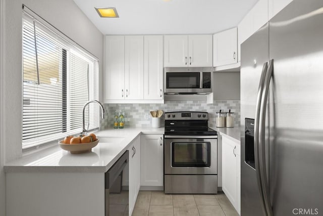 kitchen featuring backsplash, light countertops, a sink, white cabinets, and stainless steel appliances
