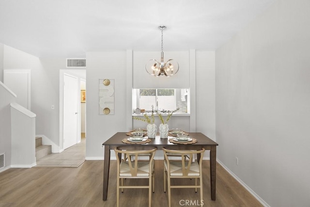 dining space with a notable chandelier, stairs, baseboards, wood finished floors, and visible vents