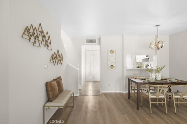 corridor featuring an inviting chandelier, baseboards, wood finished floors, and visible vents