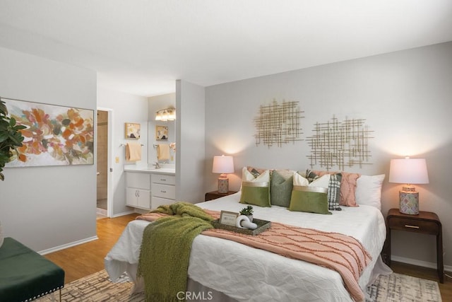 bedroom with baseboards, ensuite bathroom, and light wood-type flooring