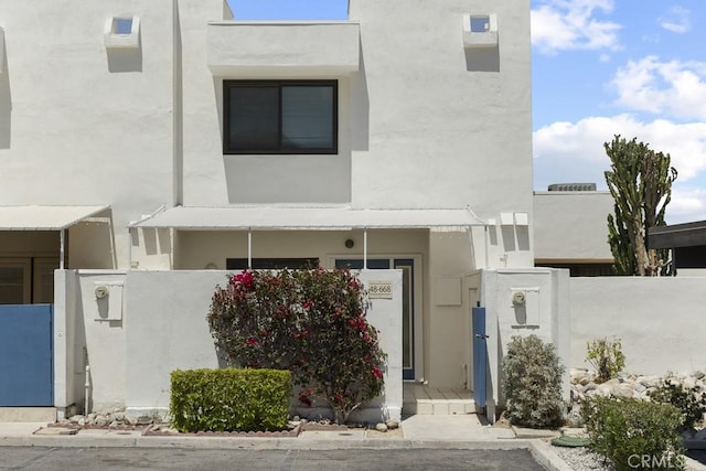 view of front of home featuring stucco siding, a gate, and fence