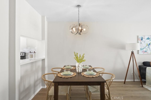 dining space featuring baseboards, light wood-style flooring, and a chandelier