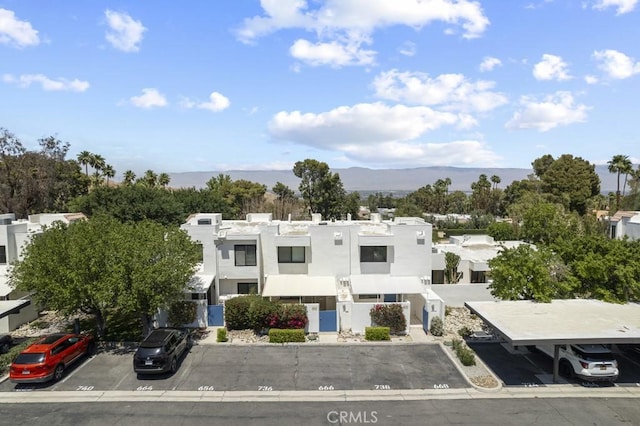 view of front facade with a mountain view, stucco siding, and uncovered parking