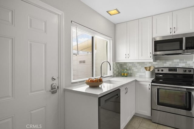 kitchen with a sink, appliances with stainless steel finishes, backsplash, and light countertops