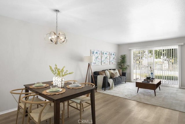 dining space featuring an inviting chandelier, baseboards, and wood finished floors