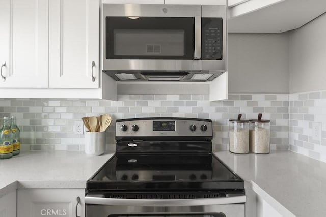 48668 Desert Flower Dr, Palm Desert, CA 92260 - kitchen with stainless steel appliances, white cabinetry, and backsplash