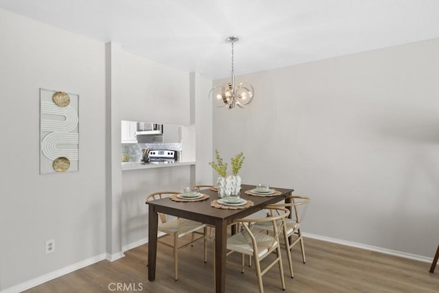 dining room featuring baseboards, wood finished floors, and an inviting chandelier