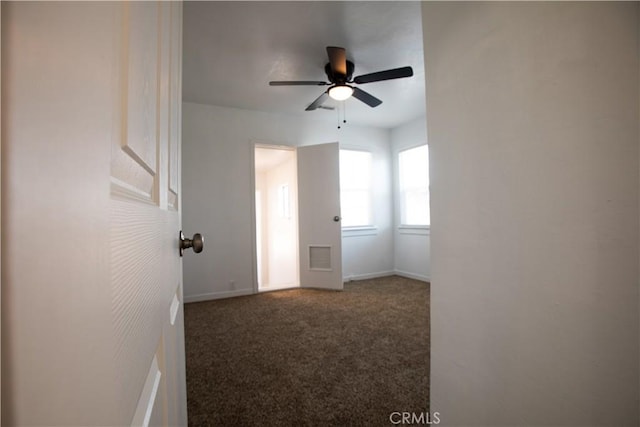 empty room featuring carpet floors, ceiling fan, and baseboards