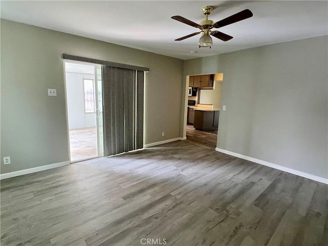 unfurnished living room with baseboards, dark wood finished floors, and ceiling fan