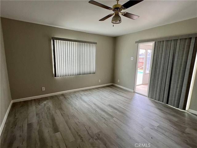 empty room featuring a ceiling fan, baseboards, and wood finished floors