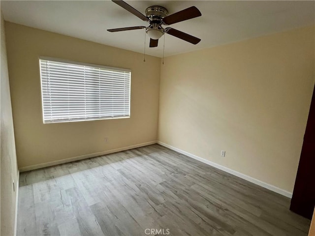 spare room with baseboards, ceiling fan, and wood finished floors