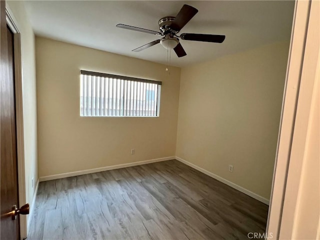 spare room with baseboards, ceiling fan, and wood finished floors