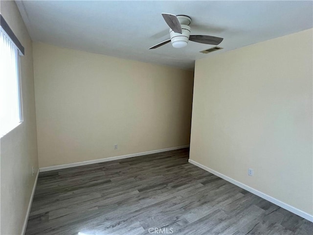 unfurnished room with visible vents, dark wood finished floors, ceiling fan, and a healthy amount of sunlight