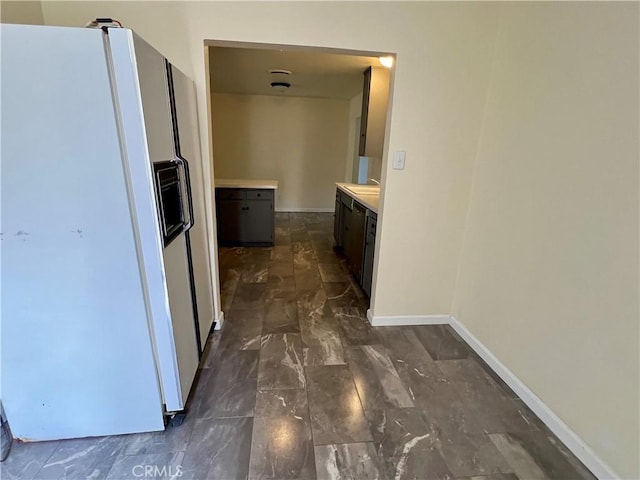 corridor featuring baseboards, a sink, and marble finish floor