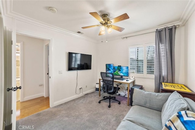 carpeted home office with crown molding, ceiling fan, visible vents, and baseboards