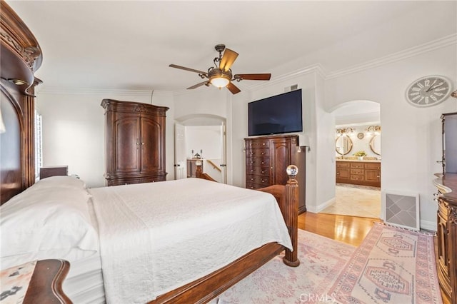 bedroom featuring visible vents, arched walkways, light wood-style flooring, and ornamental molding