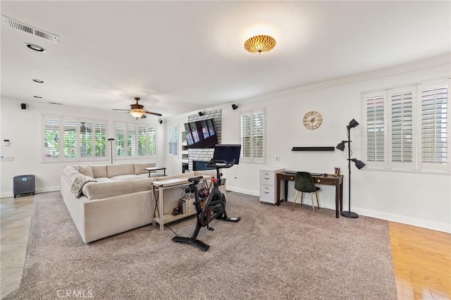 living area with ceiling fan, visible vents, ornamental molding, and baseboards