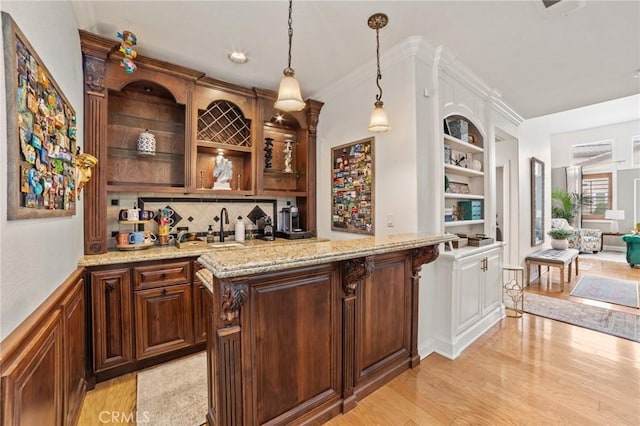 bar with hanging light fixtures, a sink, light wood-style floors, wet bar, and decorative backsplash
