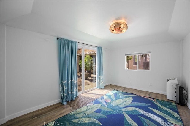 bedroom featuring baseboards, wood finished floors, and access to exterior