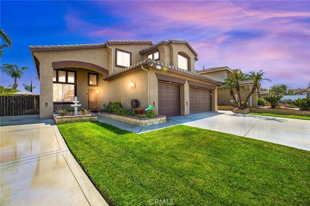 mediterranean / spanish home featuring fence, stucco siding, concrete driveway, a lawn, and a tiled roof