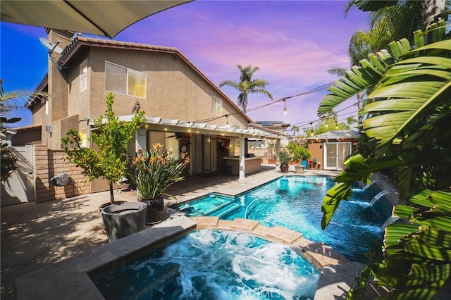 view of pool featuring a patio area, a pool with connected hot tub, and fence